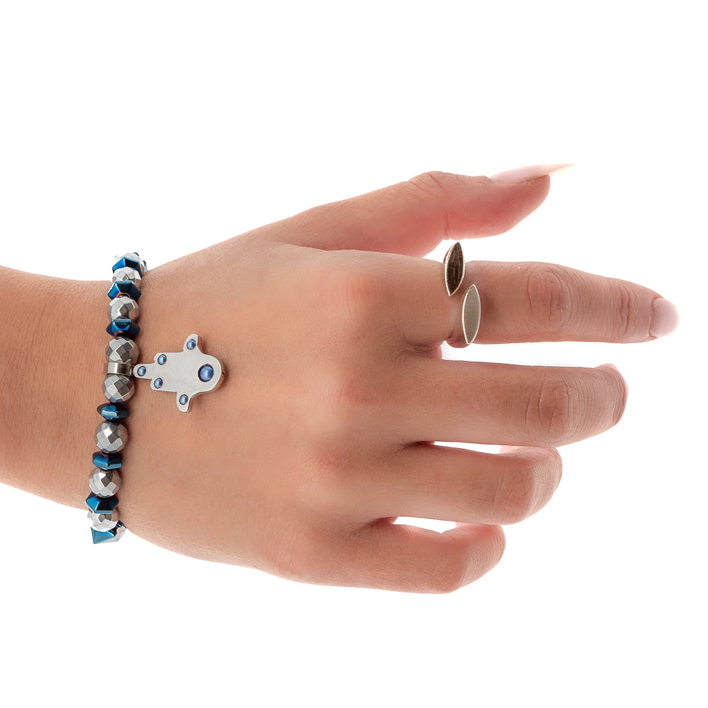 The hand model radiates positivity while showcasing the elegance of the Positive Hamsa Bracelet, featuring silver faceted hematite beads, blue hematite pyramid beads, and a symbolic Hamsa charm.