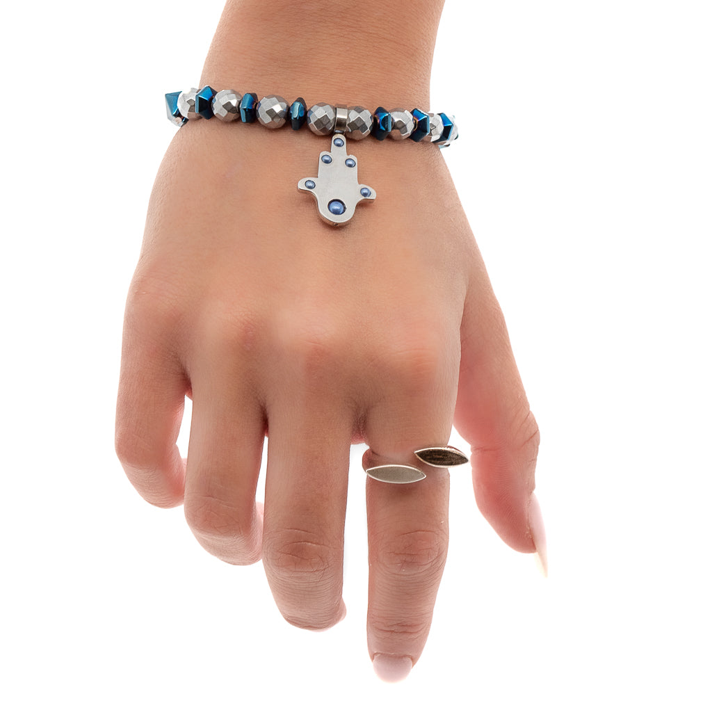 See how the Positive Hamsa Bracelet adorns the hand model's wrist with its silver hematite beads, blue hematite pyramid beads, and the powerful Hamsa charm.