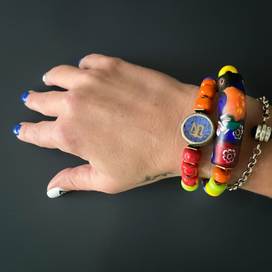 Experience the captivating beauty of the Spring Vibes Bracelet as it adorns the hand model's wrist, showcasing the colorful Indian beads, gold hematite spacers, and unique glass tube bead.