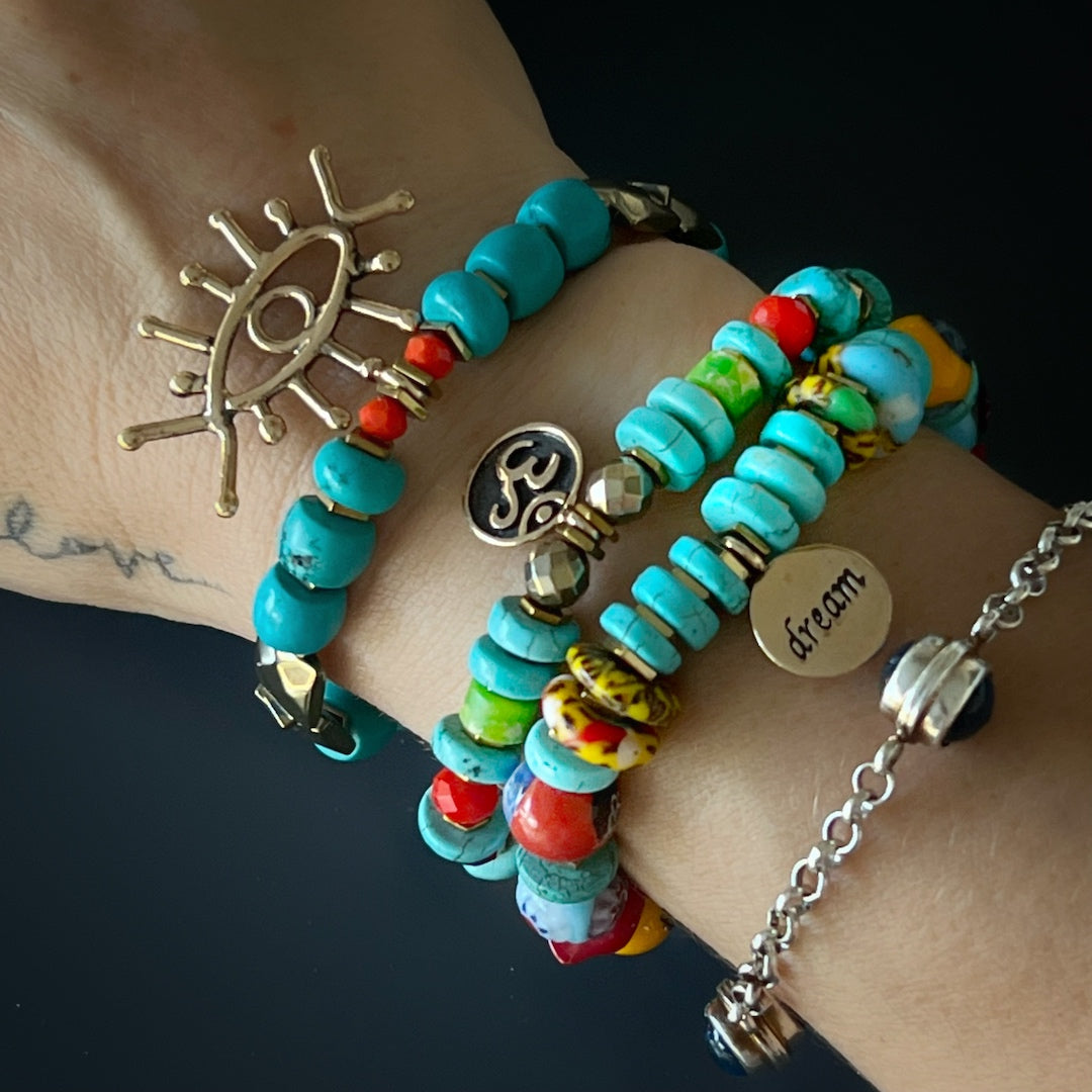 The hand model effortlessly showcases the elegance and spiritual energy of the Turquoise Long Lash Bracelet, adorned with turquoise beads, a sparkling Swarovski crystal, hematite, and a brass evil eye charm.