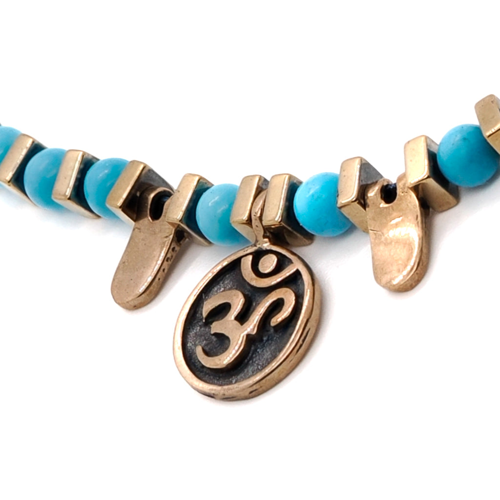 Close-up of the Turquoise Spiral Necklace, highlighting the bronze OM mantra charm and the unique spiral design.