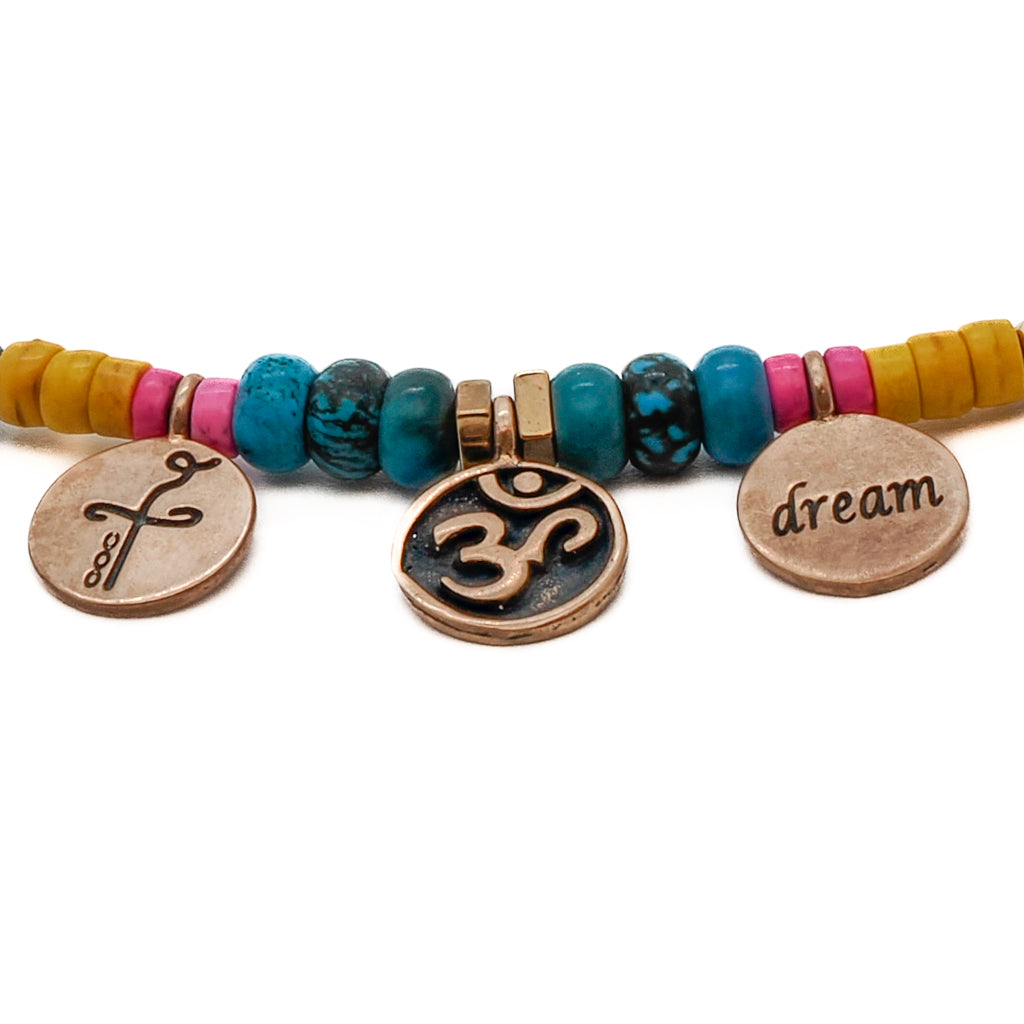Let the Yogi Dream Anklet be a gentle reminder of your spiritual journey, featuring bronze gold-plated Om-Dream and Heal charms, turquoise stone beads, and African blue beads, symbolizing balance, healing, and the potential for personal transformation.